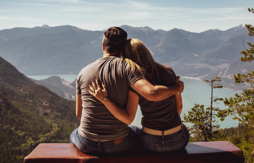 Image représentant le bien être du couple : un couple en face d'un paysage, un lac et des montagnes